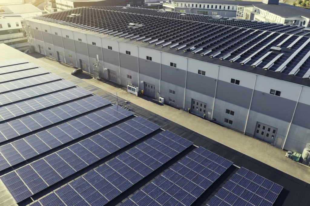 Große Fabrikhalle mit Solarpanelen auf dem Dach.